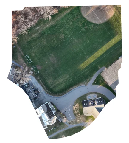 RGB aerial orthomosaic of the surveyed area: playing fields, tree line, access road and campus buildings.